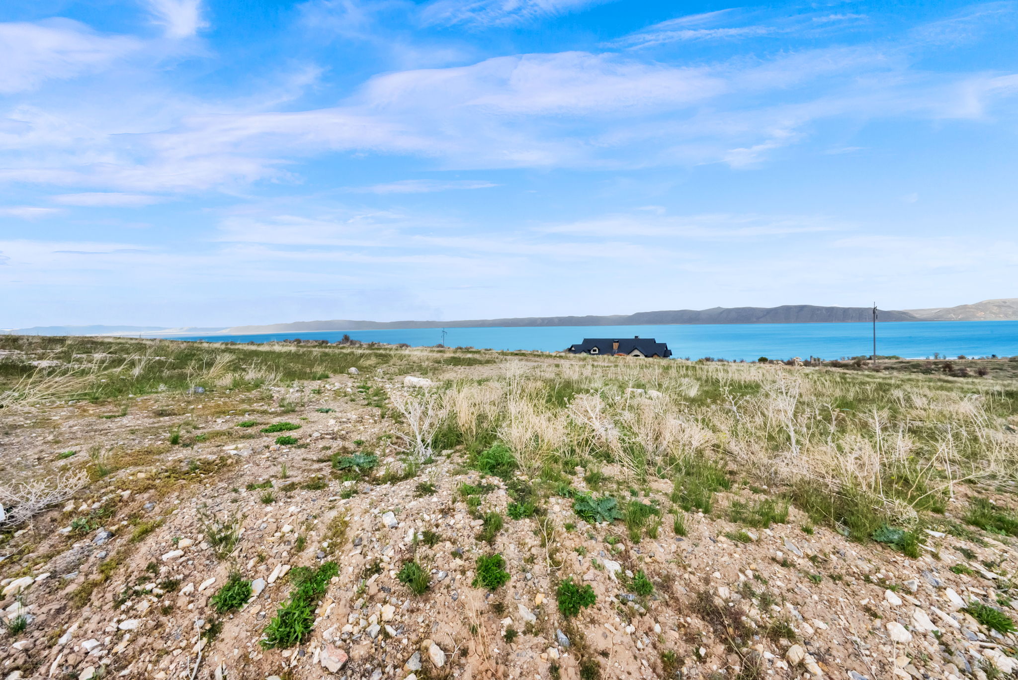 Expansive land parcel featuring natural grasses and distant water frontage