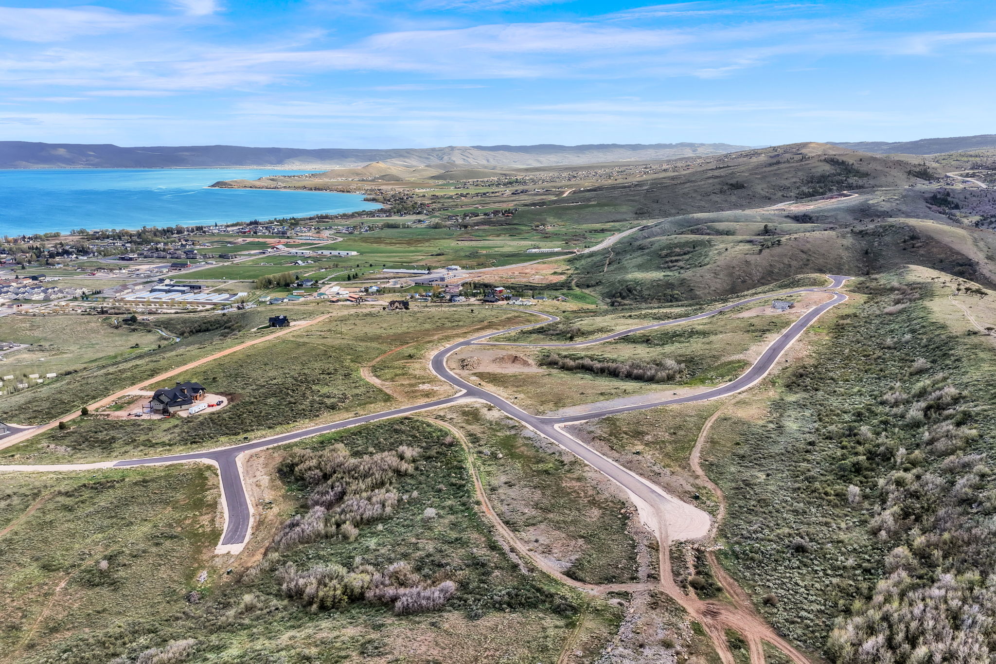 Aerial landscape featuring a large body of water, rolling hills, and a network of paved roads