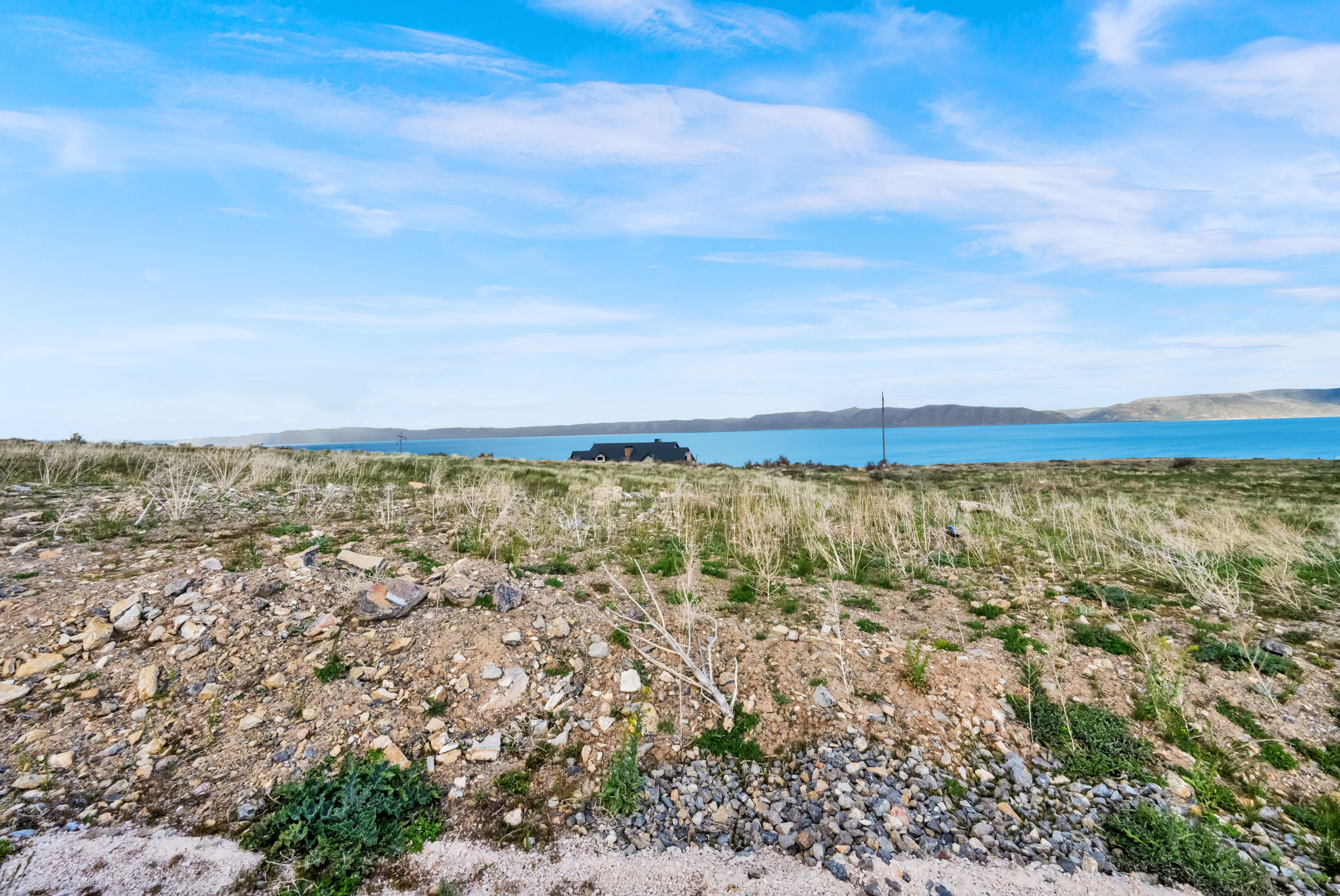 Expansive land parcel featuring natural terrain and distant water body with a visible shoreline