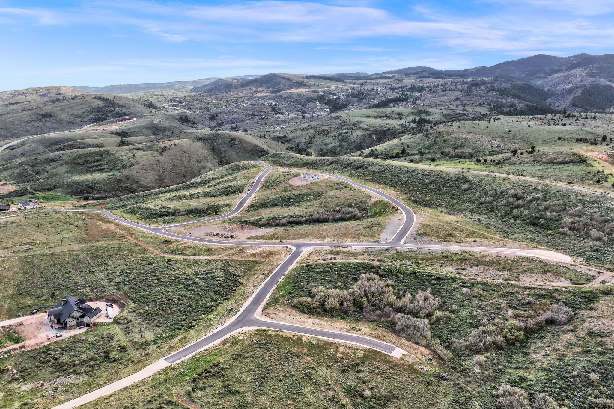 Expansive mountain landscape featuring numerous paved roads and a distant residential structure