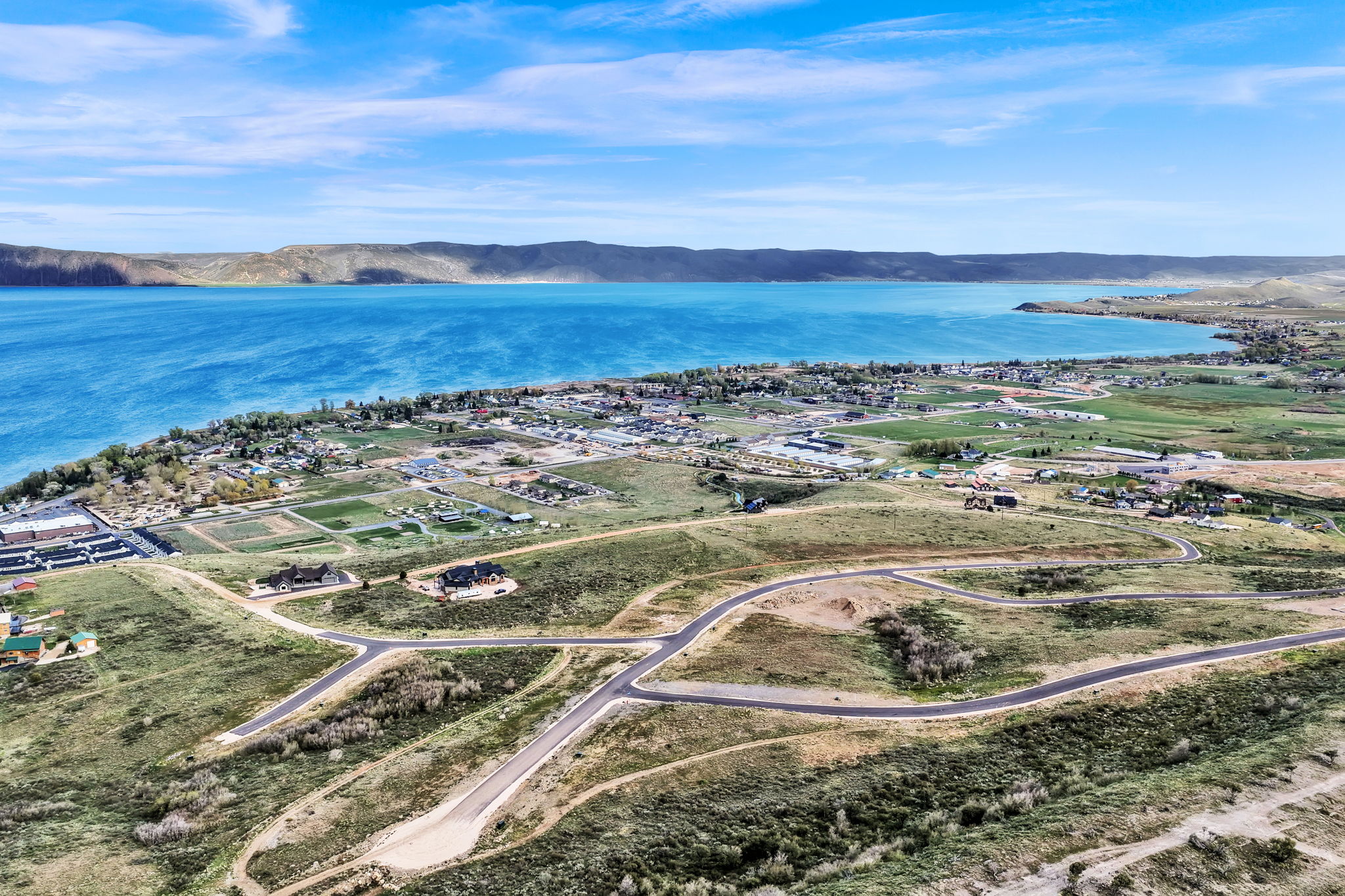 Expansive land parcel featuring paved roadways, graded lots, and distant lake frontage