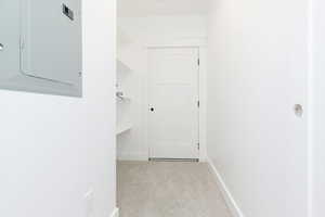 Corridor featuring electric panel and light colored carpet