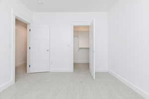 Unfurnished bedroom with light colored carpet and a spacious closet