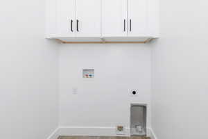 Laundry room with hookup for a washing machine, cabinet space, electric dryer hookup, and wood finished floors