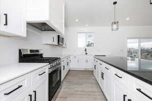 Kitchen featuring appliances with stainless steel finishes, white cabinets, pendant lighting, dark stone countertops, and recessed lighting