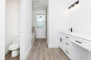Bathroom with vanity, a garden tub, light wood-style floors, and recessed lighting