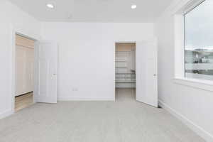 Unfurnished bedroom featuring light colored carpet, a spacious closet, and recessed lighting