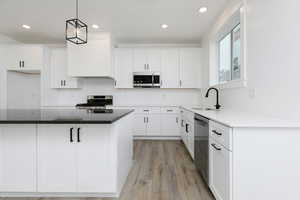 Kitchen featuring white cabinetry, appliances with stainless steel finishes, light wood-type flooring, recessed lighting, and a kitchen island