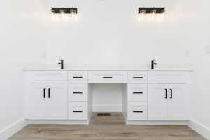 Full bath featuring double vanity and light wood-type flooring