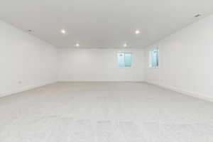 Empty room with light colored carpet and recessed lighting