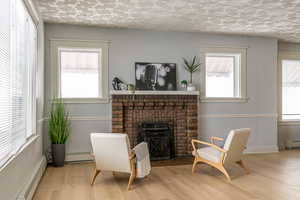 Sitting room featuring a baseboard radiator, wood finished floors, baseboard heating, and a brick fireplace