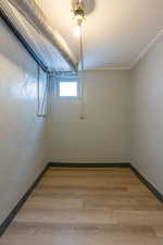 Empty room featuring light wood-style flooring, a textured ceiling, and a textured wall