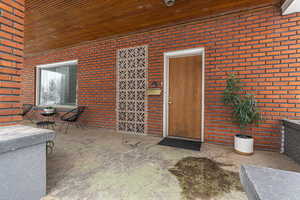 View of exterior entry with brick siding and a patio area