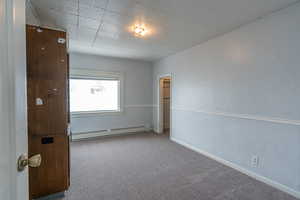 Carpeted empty room with baseboard heating and baseboards