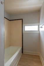 Bathroom with light wood finished floors and shower / washtub combination