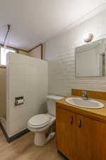 Full bath with vanity, light wood-style floors, and tiled shower