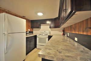 Kitchen featuring white appliances, dark brown cabinetry, and light wood-style floors