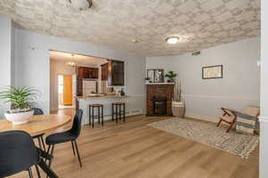 Dining area featuring light wood-style floors, a baseboard radiator, a fireplace, and a chandelier