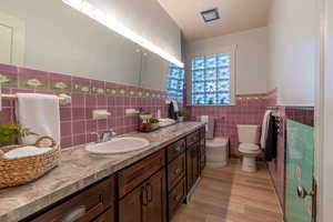 Bathroom featuring a wainscoted wall, tile walls, vanity, and light wood-style floors