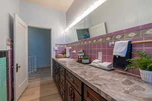 Bathroom featuring vanity, tile walls, light wood finished floors, and wainscoting