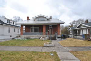 Bungalow-style home featuring a porch, brick siding, and a chimney