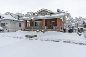 View of front facade with a porch, a chimney, and brick siding