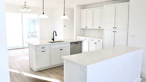 Kitchen featuring white cabinetry, pendant lighting, a kitchen island with sink, light wood-type flooring, and light stone countertops (pictures of home previously built)