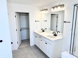 Bathroom featuring double vanity and a spacious closet (pictures of home previously built)