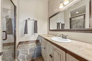 Full bathroom with a marble finish shower, vanity, and dark stone finish flooring