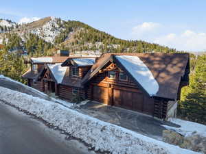 Cabin with log siding, a mountain view, and a chimney