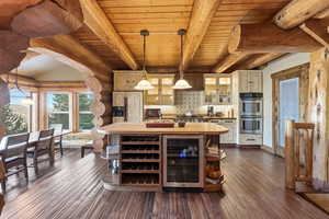Bar area with glass insert cabinets, wood counters, rustic walls, wine cooler, and hanging light fixtures