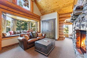 Living room with a fireplace, high vaulted ceiling, wood ceiling, carpet floors, and log walls