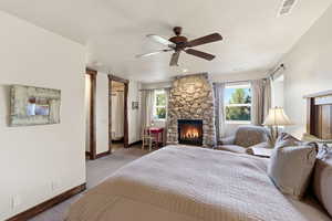 Carpeted bedroom with multiple windows, a fireplace, and ceiling fan