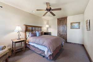 Carpeted bedroom featuring a ceiling fan and baseboards