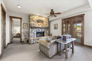 Living room with light carpet, a fireplace, and a ceiling fan