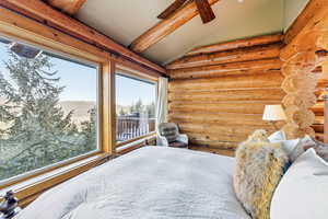 Bedroom with log walls, vaulted ceiling, a mountain view, and ceiling fan