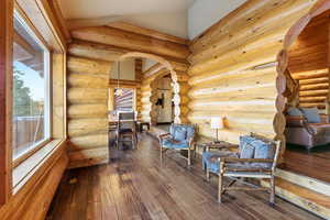 Living area featuring arched walkways, dark wood finished floors, lofted ceiling, and rustic walls