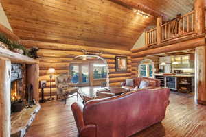 Living area with wooden ceiling, a fireplace, plenty of natural light, wine cooler, and high vaulted ceiling