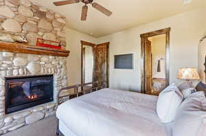 Bedroom with carpet floors, connected bathroom, a fireplace, and ceiling fan