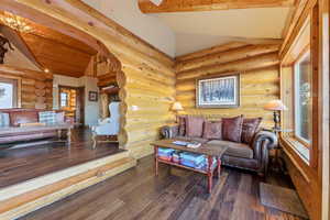Living room with log walls, hardwood / wood-style flooring, and arched walkways