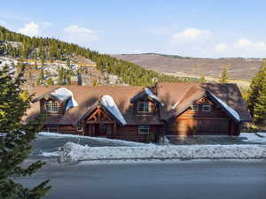 Log home featuring a chimney, log siding, and a garage