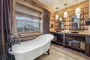 Bathroom featuring double vanity, rustic walls, and a freestanding bath