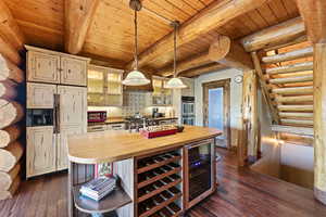 Kitchen with glass insert cabinets, paneled built in fridge, rustic walls, pendant lighting, and beverage cooler
