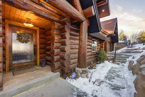 Snow covered property entrance with log siding