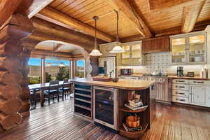 Bar area with pendant lighting, beverage cooler, glass insert cabinets, butcher block countertops, and open shelves