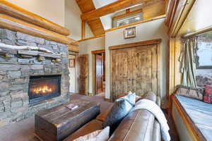 Living area featuring carpet, a fireplace, high vaulted ceiling, and a wood ceiling with exposed beams