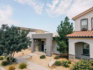View of front of home featuring stone siding, stucco siding, and a tiled roof