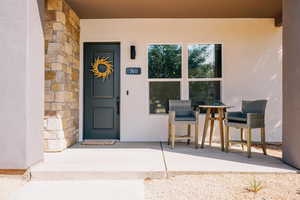 Doorway to property with stone siding, stucco siding, and covered porch