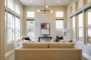 Carpeted living area featuring a chandelier and a high ceiling