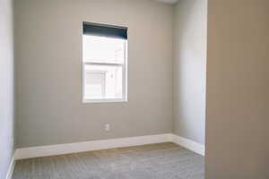 Unfurnished room featuring light carpet and baseboards